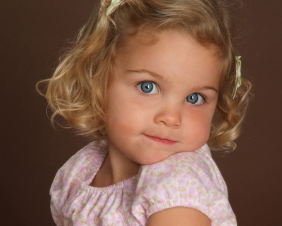 Little Girl With Big Blue Eyes And Curly Blonde Hair With Her Chin